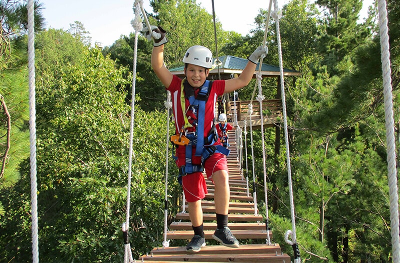Young boy walks across suspension bridge