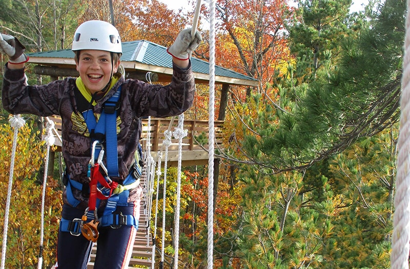 Young girl walks across suspension bridge smiling
