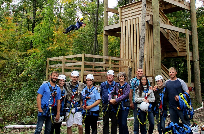 Group poses for picture while man zips above them