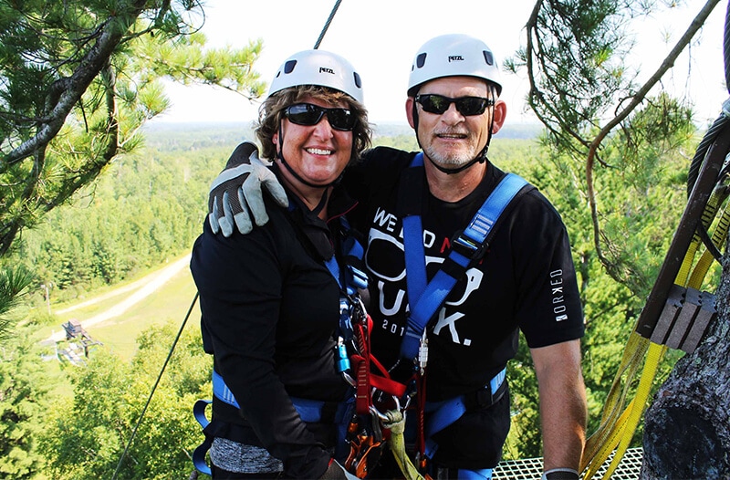 Couple poses before they zip over the brainerd trees